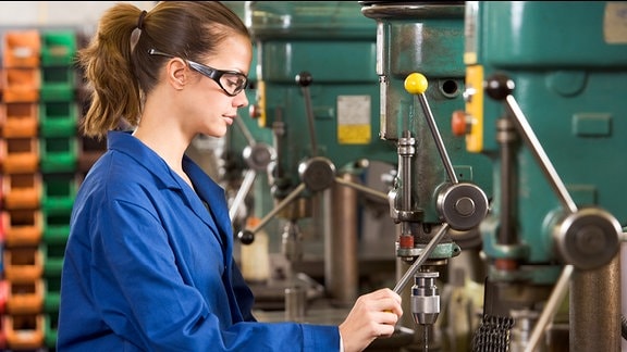 Ein junge Frau arbeitet an einer Bohrmaschine.