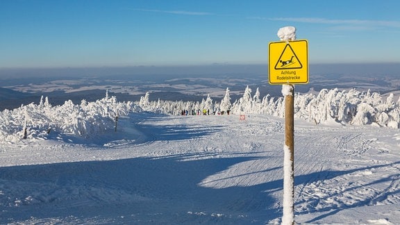 Rodelstrecke mit Hinweisschild im Vordergrund