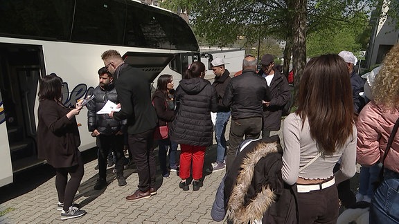 Vor einem Reisebus stehen Geflüchtete Menschen und Mitarbeiter der Verwaltung des Erzgebirgskreises. 