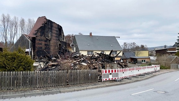 Eine Straße mit einem abgebrannten Haus und Absperrzaun