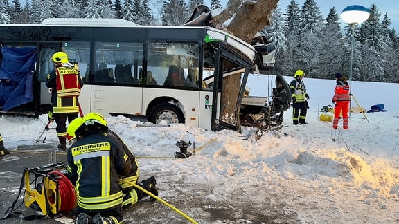 Feuerwehrleute befinden sich im Einsatz am verunglückten Bus.