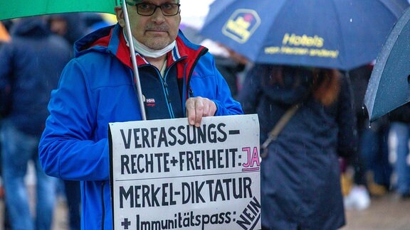 Auf dem Marktplatz von Annaberg-Buchholz steht ein Mann mit einem Schild mit der Aufschrift "Verfassungsrechte + Freiheit: Ja, Merkel-Diktatur + Immunitätspass: Nein"