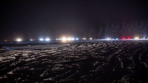Beleuchtete Pkw in der Dunkelheit in verschneiter Landschaft
