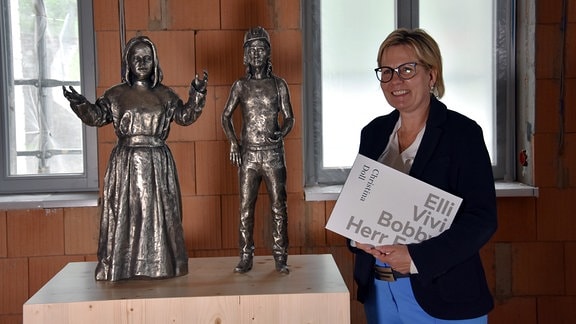 Die sächsische Kulturministerin Barbara Klepsch steht neben zwei  Skulpturen, einem Engel und einem Bergmann. 