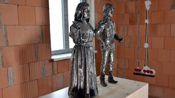 Zwei Skulpturen auf einem Holzsockel: ein Engel und ein Bergmann. 