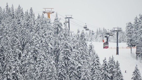 Unter der winterlichen Fichtelbergschwebebahn sind zwei Skifahrer unterwegs.