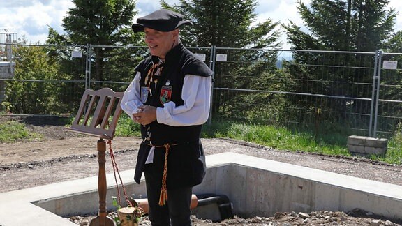 Der Türmer der Stadt Schwarzenberg, Gerd Schlesinger, spricht in Uniform am Fundament der Friedensglocke auf dem Fichtelberg.