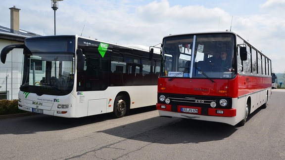 Ein roter Ikarus-Bus steht neben einem modernen Linienbus.