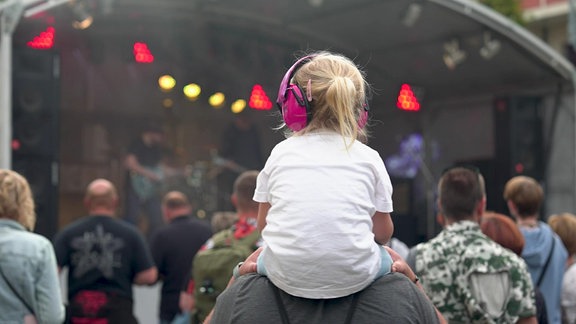 Kind auf Papas Schultern vor bunt beleuchteter Bühne beim Tag der Sachsen in Aue