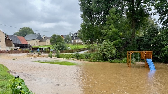 EIn Bach tritt über die Ufer in einem Dorf. 