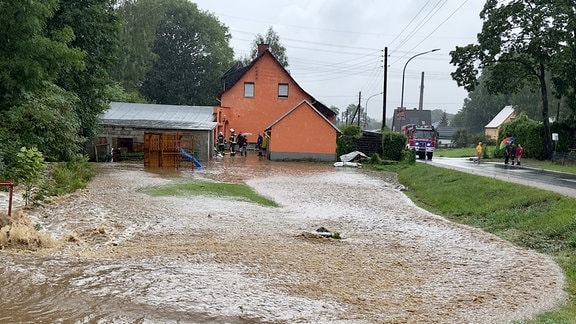 EIn Bach tritt über die Ufer in einem Dorf. 