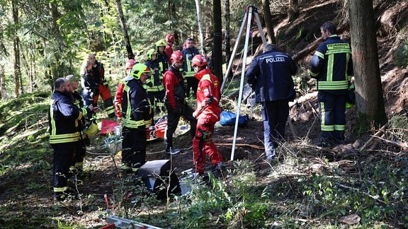 Rettungskräfte von Polizei und Feuerwehr stehen in einem Wald.