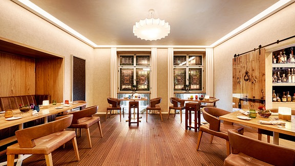 Blick in einen großen Raum eines Restaurants. der Raum ist in hochwertigem hellen Holz gestaltet, die Tische sind dezent gedeckt.