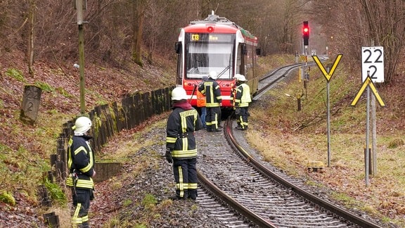 Auf der Bahnstrecke zwischen Chemnitz und Aue ist am 21.12.2023 die Chemnitz-Bahn gegen einen auf den Gleisen liegenden Baum gefahren. In Höhe der Ortschaft Burkhardtsdorf war Endstation. Feuerwehrleute begutachten die Strecke und den Schaden.