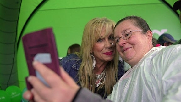 Rocksängerin Petra Zieger steht bei einer Autogrammstunde beim Tag der Sachsen in Aue neben einer Besucherin, die ein Selfie mit der Sängerin macht.