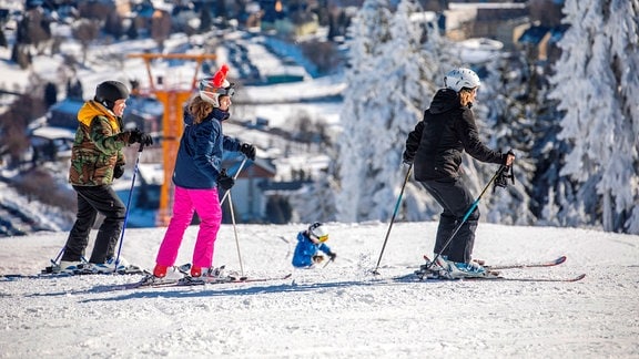 Menschen in bunten Skianzügen stehen an einem Schneehang und fahren jeden Moment ins Tal richtung Oberwiesenthal. Zum Winterferienstart 2020 war am Fichtelberg jede Menge los. 