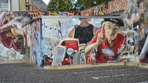 Straßenkunst des Künstlers "Tasso" in Zwickau: Eine alte Frau mit erhobenem Zeigefinger und ein Oldtimer