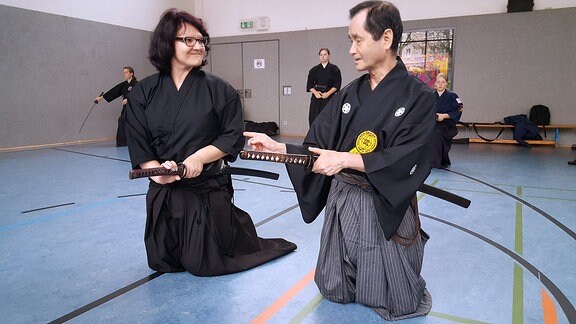 Ein japanischer Schwertkunst-Großmeister korrigiert eine Schülerin