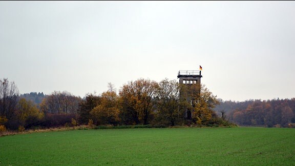 Blick über ein Feld auf einen alten Grenzturm
