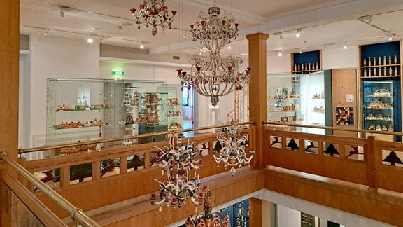 In einem offenen Museumsraum hängen erzgebirgische Leuchter, dahinter stehen Vitrinen mit erzgebirgischer Volkskunst.