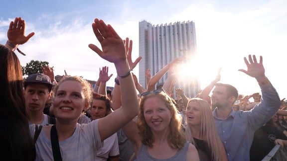 Menschen trecken bei einem Konzert die Hände in die Höhe.