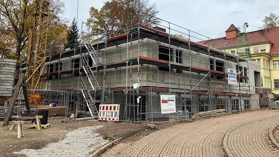 Blick auf einen eingerüsteten Betonrohbau mit Baukran