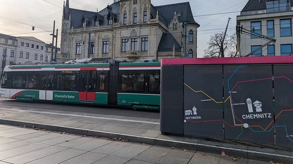 Auf dem Bahnhofsvorplatz Chemnitz fährt eine City-Bahn an einem gestalteten Wartehäuschen vorbei.