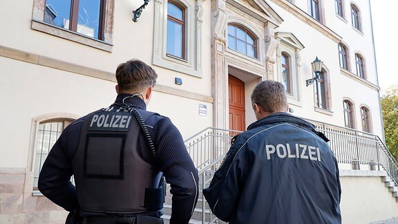 Zwei Polizisten stehen vor einem Schulgebäude in Chemnitz.