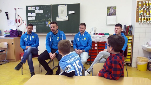 CFC-Spieler Chris Löwe, Geschäftsstellenleiter Tommy Haeder, Manuel Reutter und Niclas Walther in einer Schulklasse.