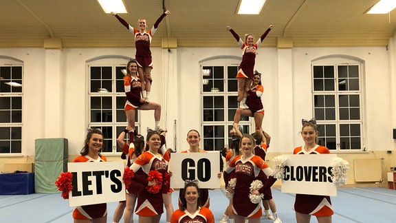 Cheerleader machen eine Pyramide und halten Schilder