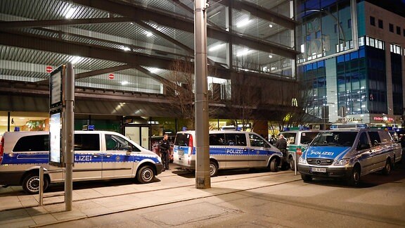 Polizisten und Polizeiautos stehen vor Parkhaus bei Nacht