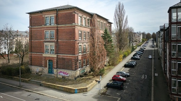 Ein großes Backsteinhaus steht in einer Straße.