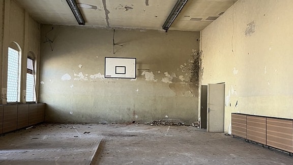 Eine verfallene Turnhalle mit Basketballbrett.