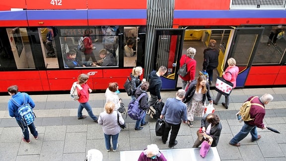 Mehrere Menschen steigen an einer Haltestelle in eine Straßenbahn in Chemnitz ein. 