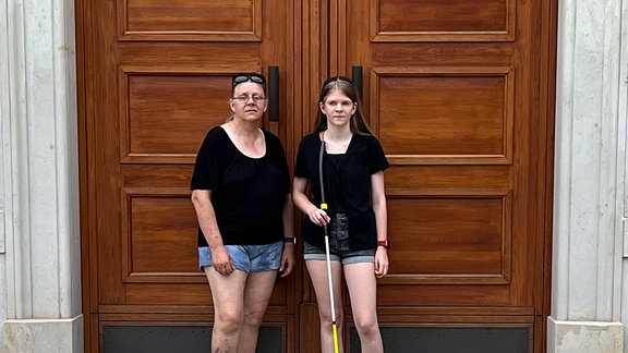 Eine Frau und ein Mädchen stehen vor einer großen Tür.