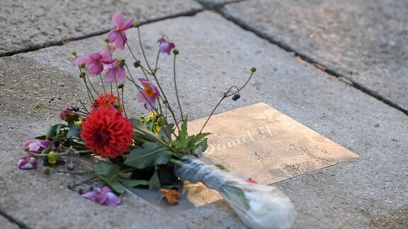 Blumen liegen an einer Gedenkplatte für den getöteten Daniel H. in Chemnitz.