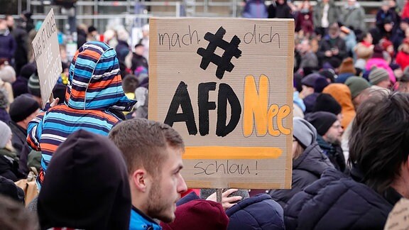 Demonstranten halten ein Plakat. 