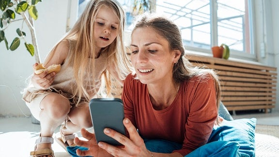 Eine Frau und ein Mädchen schauen auf ein Smartphone