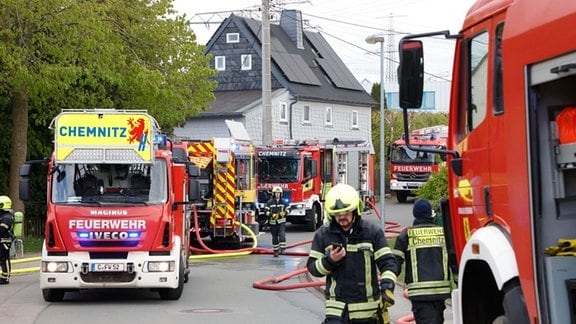 Feuerwehrleute befinden sich mit ihren Einsatzwagen auf einer Straße in Chemnitz.