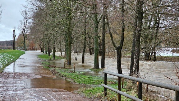 Blick auf einen überspülten Fußweg neben einem über die Ufer getretenen Bach.