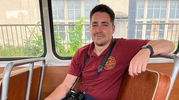 Mann mit Fotoapparat auf Passagiersitz eines restaurierten Ikarus-Buses
