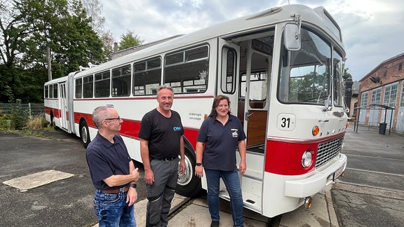 Drei Personen vor restauriertem Ikarus-Bus 