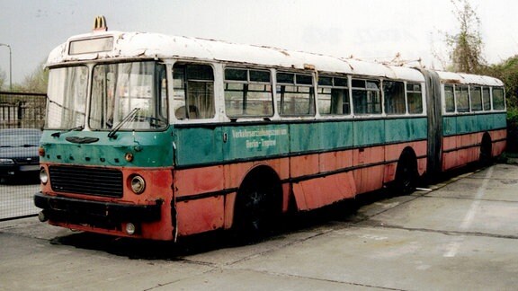 Ein alter grün-roter Bus steht auf einem Parkplatz.