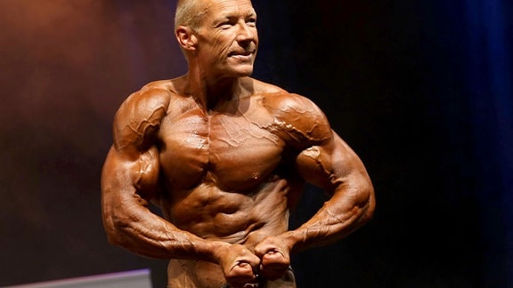 Jens Berthold, Bodybuilder, spannt seine Muskeln an.