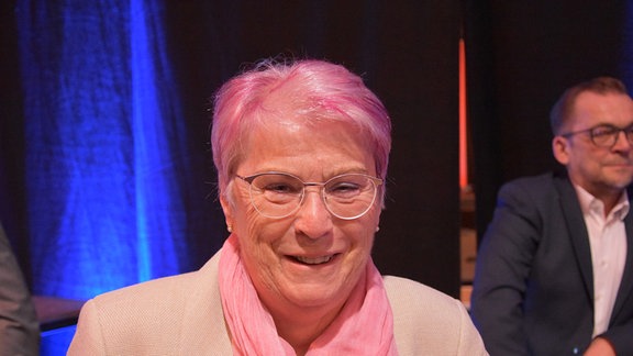 Eine Frau mit gefärbten Haaren lächelt in die Kamera