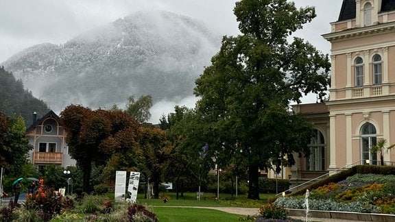 Ein schneebedeckter Berg hinter einem blühenden Park im österreichischen Bad Ischl.