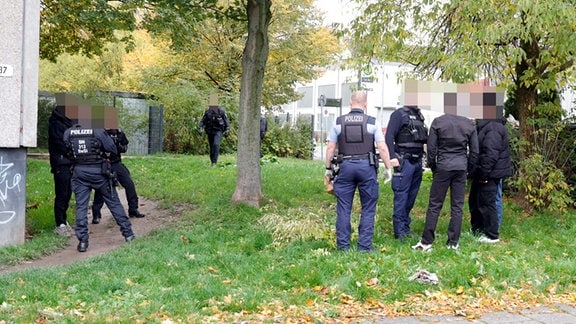 Mehrere Polizeibeamte stehen auf einer Wiese.  