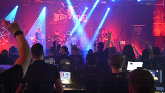 Blick über die Zuschauer zur Bühne mit Metal-Band und Schild "Metal-Battle" 