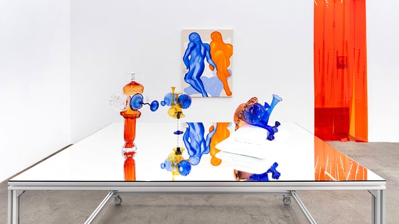 Glaskunst in blau orangenen Farben auf einem Spiegeltisch, Werke von Paul Glaw.