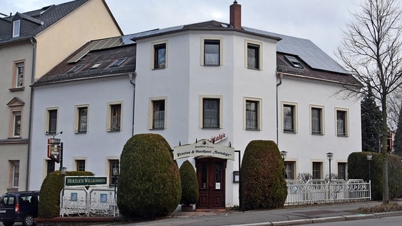 Die Pension "Nostalgie" in Chemnitz, ein weißes Eckhaus mit hohen Büschen vor der Tür.